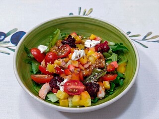 Salad with cherry tomatoes, shrimps, arugula, cucumber, feta cheese, mango, raspberries, sesame seeds.