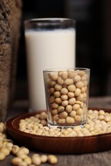 Soy milk with soybeans on wood background