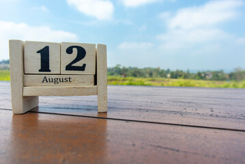 Wooden cube calendar for 12th August place on a table in a sunny day background