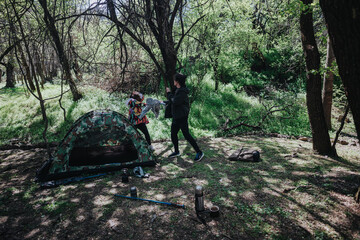 A young couple establishes their campsite in a tranquil woodland setting, complete with a...