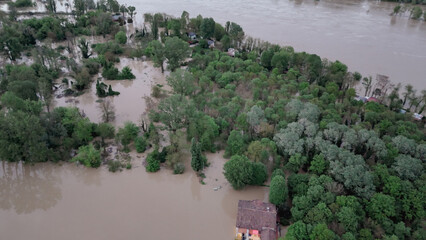 Aerial view of flooded trees and submerged land near a riverbank showcasing the impact of heavy...