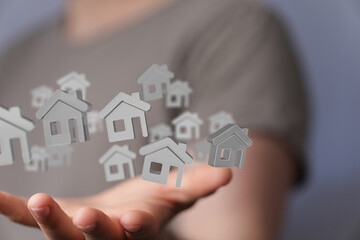 Hand holding multiple 3D house icons, symbolizing real estate, property, or home ownership.