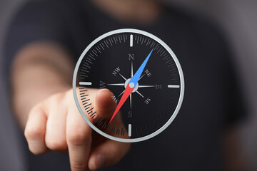 Hand pointing at a digital compass, symbolizing direction, guidance, and strategic planning.