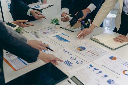 Business people discussing charts and graphs showing results of successful teamwork, stock market charts and pointing fingers on tablets in office.