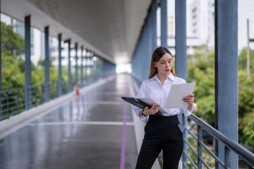 Fototapeta premium Businesswoman reading documents in modern office building corridor