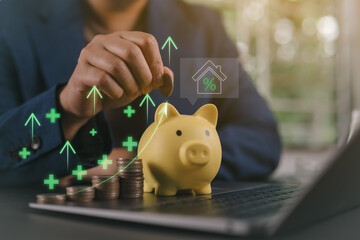Personal finance management. Businessman saving coin into piggy bank with house and interest rate...