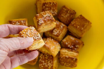 hand holding a sesame seed topped cottage cheese scone over a yellow bowl