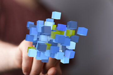 3D rendering of blue and yellow data cubes on a finger, representing digital information and...