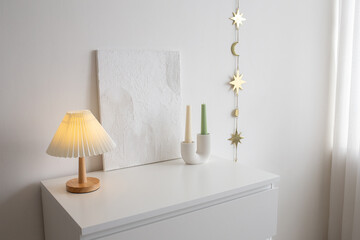 An on table lamp with corrugated shade, painting with putty, candles in curved geometric candle...