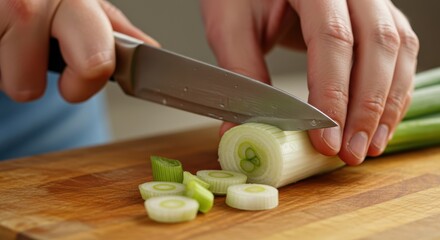 Slicing the white part of green onions with a knife on a cutting board