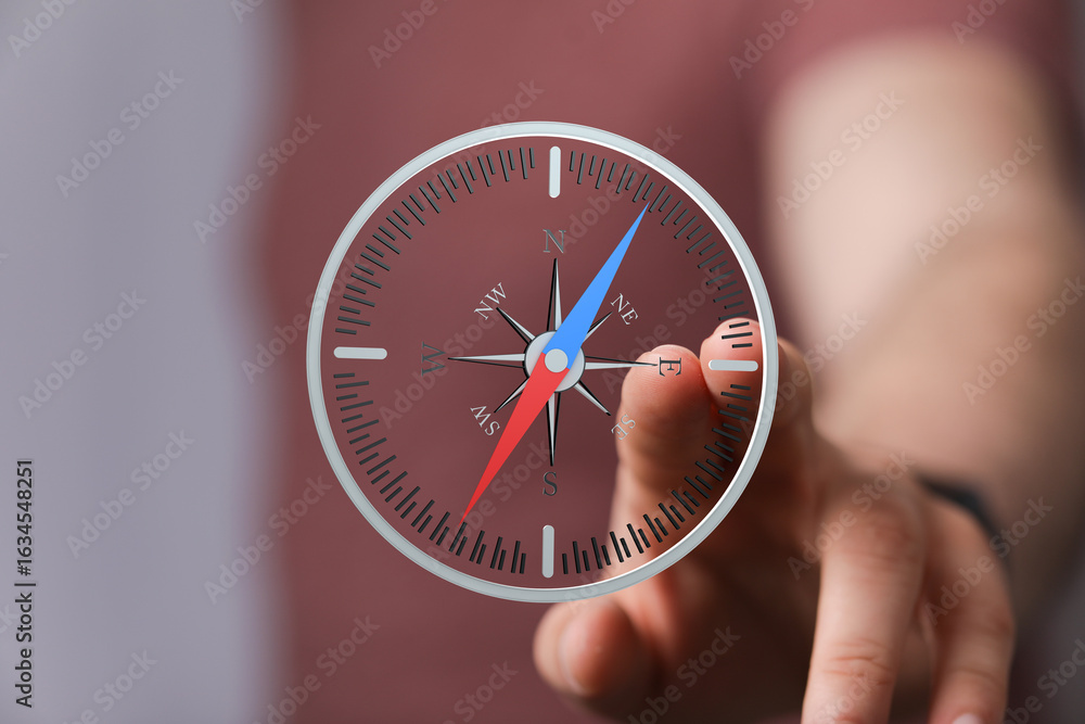 Poster close-up of a hand interacting with a digital compass interface, showing navigation and direction.