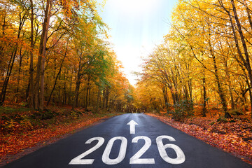 2026 and arrow on asphalt road between trees in autumn. Hope and expectation for new year