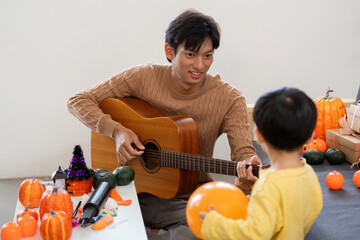 Musical Moments. Father playing guitar for son during Halloween celebration.