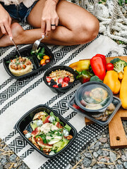 Healthy takeaway meals in lunch boxes with vegetables, fruits, and rice. Outdoor picnic, eating in...