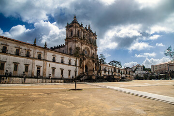 Fototapeta premium The grand and majestic facade of the Monastery of Santa Maria de Alcobaça on a sunny day, showcasing its impressive architecture and wide courtyard in Alcobaça, Portugal.