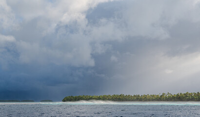 Storm approaching an atoll as waves crash on the reef barrier