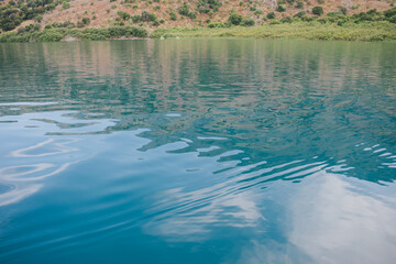 Crystal clear water of the freshwater Lake Kournas in Crete near Georgioupolis. Mountain view. Clouds reflected in the water