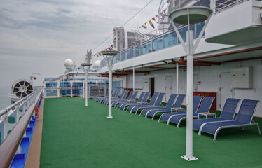 Outdoor sun deck onboard modern luxury cruiseship cruise ship liner with sun loungers and deck...