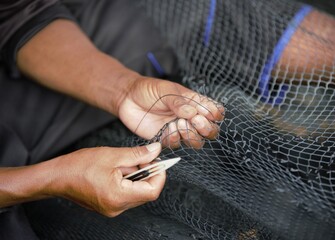 Hands of a fisherman sawing the fishing net in Pangkor Island, Malaysia