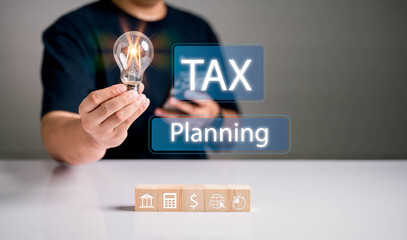Tax planning concept with businessman holding glowing light bulb and financial icons. Creative...