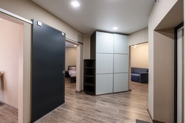 Modern interior with sliding door, wardrobe, and glimpses into a bedroom and living room. Neutral...