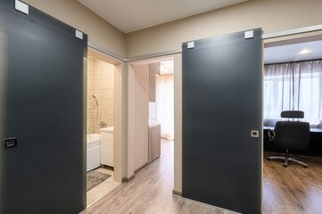 View of interior doorways with sliding doors, offering glimpses into a bathroom, kitchen, and office space