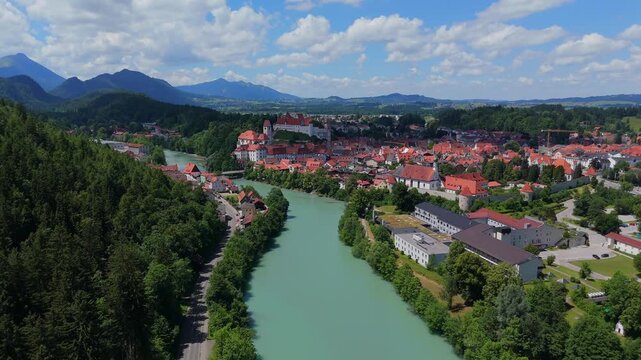 Wide aerial footage of Fussen, Germany, highlighting the Lech River, historic old town, and scenic mountain surroundings in daylight 