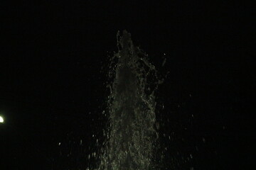 Fototapeta premium Night Fountain Water Splash Water fountain captured at night with visible splash details in the dark.