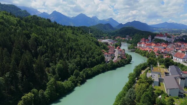 Drone video of Fussen, Germany, featuring the Lech River, historic town buildings, and scenic alpine surroundings in clear daylight 