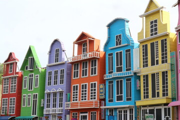 Fototapeta premium Row of Colorful Buildings in Bright Hues A picturesque row of buildings painted in vivid colors including purple, orange, and yellow, perfect for travel and design concepts.