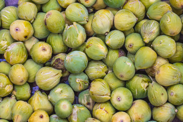 Fresh ripe green figs displayed in bulk at a fruit and vegetable market. A sweet and nutritious Mediterranean fruit, commonly used in both fresh and dried forms for culinary and health purposes