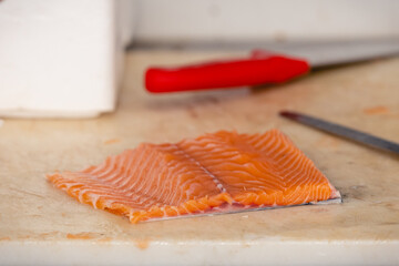 Fresh salmon fillet prepared on a kitchen cutting board, ready for cooking. A common step in home...