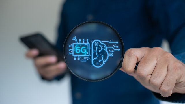 Close-up of a hand holding a magnifying glass showing 6G chip and an AI brain icon. Concept of future wireless technology, ultra-fast communication, artificial intelligence, and next-gen networks. - Powered by Adobe
