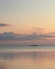 Tranquil sea view with pastel sunset clouds and soft horizon, ideal for travel, relaxation, and...
