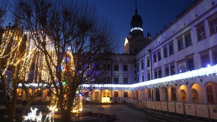 Christmas Tree and Festive Lights in Courtyard of Pomeranian Dukes’ Castle, Szczecin, Poland – Evening View Looking Up at Tower © Bluemoment72