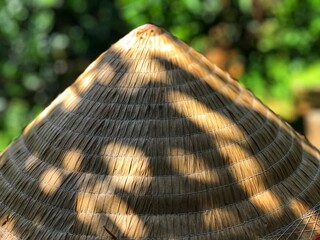 A traditional Vietnamese conical hat lit by summer sunlight, textured shadows create a warm, nostalgic rural vibe.