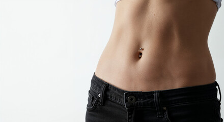 Close-up of young woman&rsquo;s waist with delicate navel piercing in bright minimalist studio.
