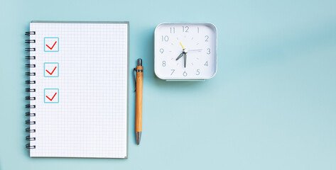 A notebook, a pen, and a clock on a blue background. Marking the correct option out of three with a...