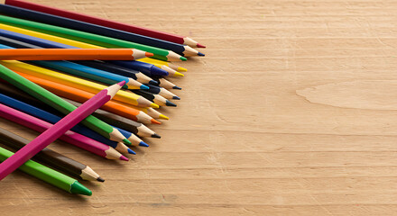 A vibrant collection of colored pencils artistically arranged on a wooden surface with copy space.