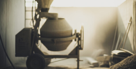 Cement mixer in a dusty room with ladder and construction materials, illustrating a raw industrial setting in the middle of renovation or building process.
