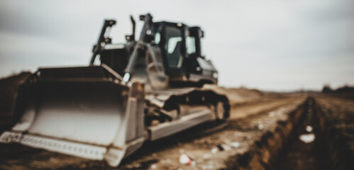 A bulldozer sits on dirt ground under a cloudy sky, capturing the heavy machinery in a moment of stillness at a rugged outdoor construction environment.