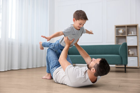 Father and son feeling comfortable to have fun together barefoot on warm floor at home. Underfloor heating