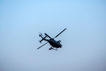 Silhouette Helicopter turning on isolated blue sky