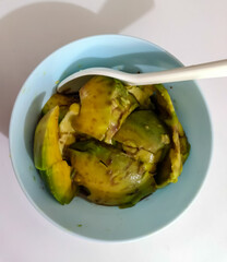 A simple blue bowl filled with freshly sliced avocado, a nutritious and healthy breakfast snack captured from above.