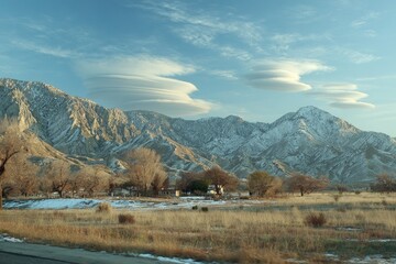 Mountain range with unusual clouds, a rural landscape, and snow-capped peaks