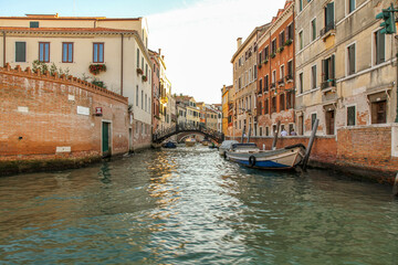 Traditional canal with boats and historical buildings in Venice, Italy.