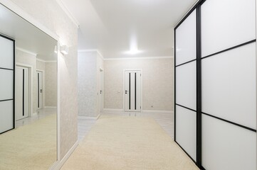 bright hallway features a large mirror, sliding wardrobe, and beige carpet. Several doors are visible along the walls