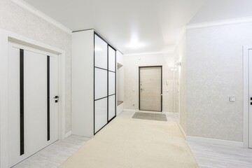 well-lit hallway with neutral tones, featuring doors, a sliding door closet, and a beige carpet