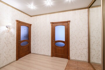 bright hallway with two wooden doors and a mirrored wardrobe. The walls are decorated with...