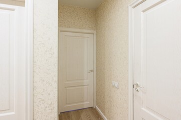 Light beige walls are complemented by wooden doors and trim. Soft natural light fills the space